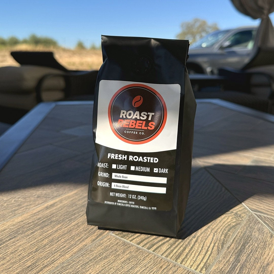 Roast Rebels 6 Bean Blend 12 oz bag outdoors on a patio table in the sun